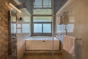 a bathroom with a window and a shower with a bench at SaffronStays Caramelo - a private swimming pool villa nestled amidst beautiful landscaping and gardens in Lavasa in Lavasa