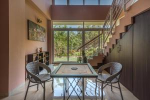a dining room with a table and two chairs at SaffronStays Caramelo - a private swimming pool villa nestled amidst beautiful landscaping and gardens in Lavasa in Lavasa