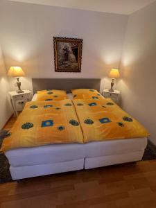 a bedroom with a bed with a yellow comforter and two lamps at Apartment Neuensien 11a in Seedorf