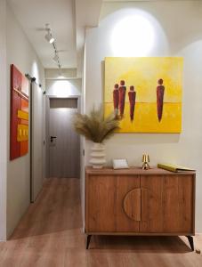 a hallway with a painting on the wall and a wooden cabinet at P Faliro Riviera Suite in Athens