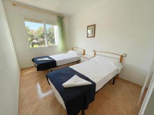 two beds in a room with a window at Apartamentos Tierra de Irta 3000 in Peniscola