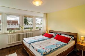 a bedroom with a bed with red pillows and two windows at Ferienwohnung Hausrosengarten in Hage