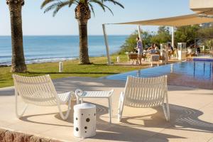 2 sedie bianche sedute accanto alla piscina di Melbeach Hotel & Spa - Adults Only a Canyamel