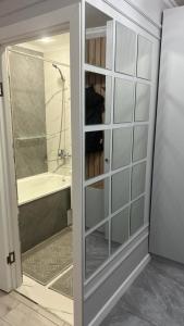 baño con puerta de cristal, bañera y ducha en Однакомнатная LUX квартира, en Ekibastuz