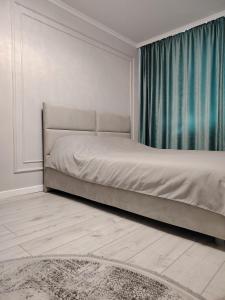 1 dormitorio con 1 cama con cortina y alfombra en Однакомнатная LUX квартира, en Ekibastuz