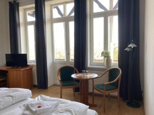 - une chambre avec une table, des chaises et des fenêtres dans l'établissement Gästehaus Musestieg, à Thale