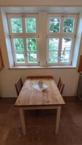 una mesa de madera con sillas en una habitación con ventanas en Rittergut Thürungen, en Kelbra