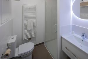 a white bathroom with a toilet and a sink at All Suites Appart Hôtel - Le Havre Centre - Les docks in Le Havre