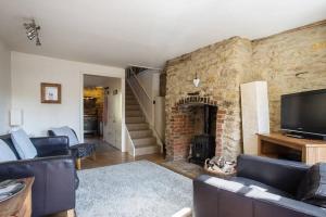 uma sala de estar com uma parede de pedra e uma lareira em Wishbone Cottage In The Cotswolds em Fairford