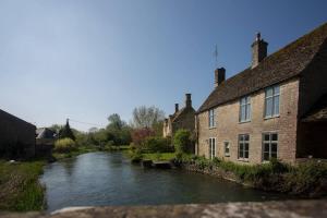 a river in front of a building next to a building at Wishbone Cottage In The Cotswolds in Fairford