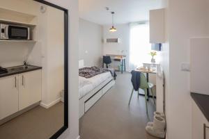 a room with a bed and a kitchen and a mirror at All Suites Appart Hôtel - Le Havre Centre - Les docks in Le Havre
