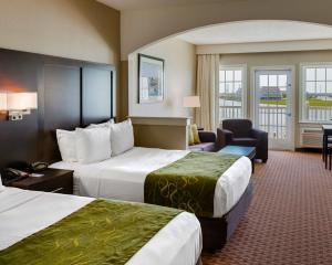 um quarto de hotel com duas camas e uma cadeira em Comfort Suites Chincoteague Island Bayfront Resort em Chincoteague