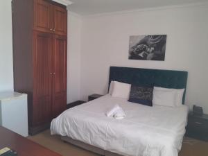1 dormitorio con cama blanca y cabecero verde en Sapphire Hotel Halevy Heritage, en Bloemfontein