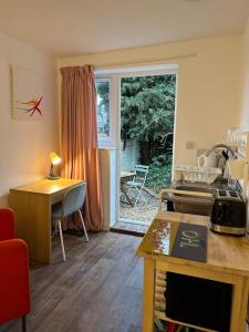 eine Küche mit einem Tisch und einem Schreibtisch und einem Fenster in der Unterkunft Garden Apartment with free Parking and EV in Bristol