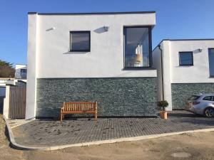 a wooden bench sitting in front of a building at Relax in style at my stunning Holywell Beach home in Holywell Bay