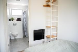 een slaapkamer met een bed en een televisie en een badkamer bij Huisje Kerkepad in Gorredijk
