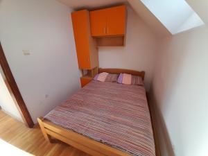 a small bed in a small room with orange cabinets at Apartmani Nova Zova in Zlatibor