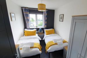 two beds in a small room with yellow pillows at The Mariners' Beacon Torquay in Torquay