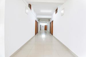 an empty corridor with white walls and white tile floors at FabHotel Raj Residency Madikeri in Madikeri