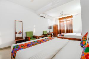 a bedroom with two beds and a living room at FabHotel Raj Residency Madikeri in Madikeri