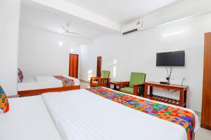 a hotel room with two beds and a tv at FabHotel Raj Residency Madikeri in Madikeri