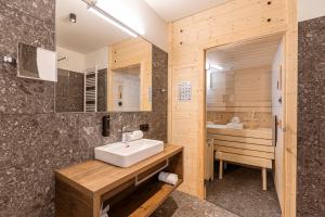 ein Badezimmer mit einem weißen Waschbecken und einer Badewanne in der Unterkunft Almresort Sonnenalpe Nassfeld by ALPS RESORTS in Sonnenalpe Nassfeld
