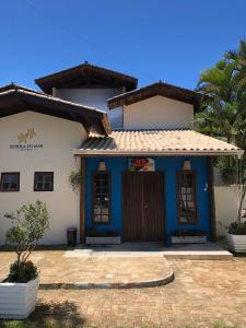 a blue and white house with a palm tree at Pousada Estrela do Mar in Maresias