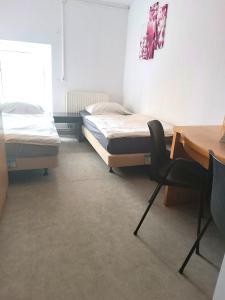 two beds in a room with a desk and a chair at Hostel Krośnieńska 12 in Zielona Góra