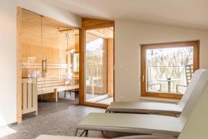 Habitación con silla y baño con ventana en Almresort Sonnenalpe by ALPS RESORTS en Sonnenalpe Nassfeld