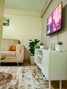 a living room with a couch and a tv on the wall at Cosy Homes Eldoret in Eldoret