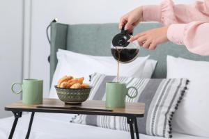 a person pouring coffee into green cups on a table at Arieni Places in Corfu