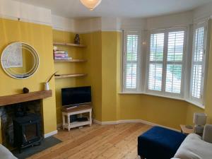 a living room with yellow walls and a flat screen tv at Stunning Victorian Dartmoor House in Yelverton