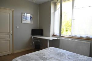 a bedroom with a bed and a desk and a window at Jardin Madeleine in Morlaix