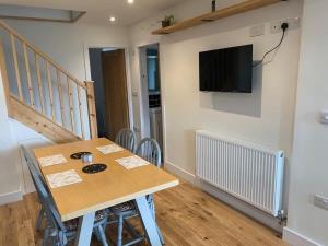 a dining room with a table and a television on a wall at Stunning Hillside House in Langport