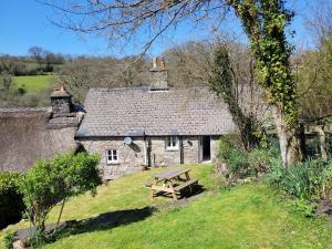 ein altes Cottage aus Stein mit einem Picknicktisch davor in der Unterkunft The Old Post Office A cosy rural gem - Dartmoor in Widecombe in the Moor