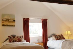 a bedroom with two beds and a window at The Old Post Office A cosy rural gem - Dartmoor in Widecombe in the Moor