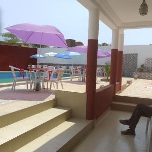 a person sitting on a balcony with tables and umbrellas at Chez Mimi in Toubab Dialaw