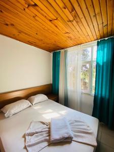 a bedroom with a bed with a wooden ceiling and a window at ZÜMRÜT PANSİYON Side in Side