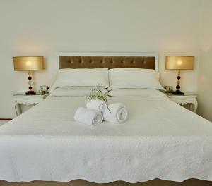 ein weißes Bett mit Handtüchern und zwei Lampen in der Unterkunft Casale Mongiusti 1961 in Musano