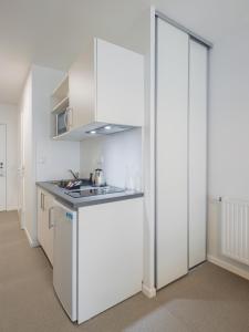 a white kitchen with a sink and a refrigerator at All Suites Appart Hôtel - Le Havre Centre - Les docks in Le Havre