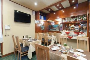 a restaurant with tables and chairs and a television at Hotel Fiorella Milano in Milan