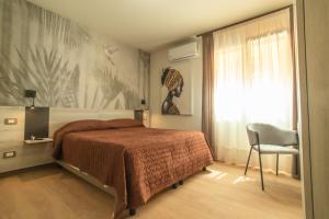 a bedroom with a bed and a chair and a window at Hotel Nautic in Lampedusa