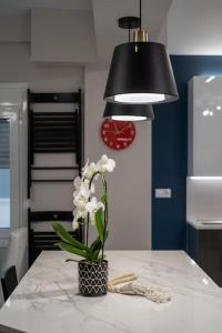 a table with a black lamp and a vase with white flowers at Athens new semi basement in Athens