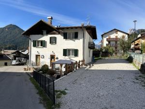 a white house with a fence next to a road at B&B Meubl&egrave; Giustina in Auronzo di Cadore