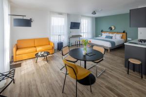 All Suites Appart Hotel Le Havre في لو هافر: غرفة فندقية بسرير وطاولة وكراسي