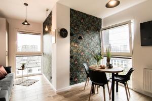 a dining room and living room with a table and chairs at Parrot - 77 Apartments Wigury - Dostęp na KOD - Parking - Smaczna Kawa - Centrum - Blisko Piotrkowska - Galeria - Widok na miasto - Klimatyzacja - 7 piętro - FV in Łódź