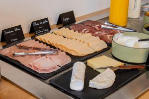 a counter with cheese and meats and a table of food at All Suites Appart Hôtel - Le Havre Centre - Les docks in Le Havre