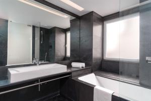 a bathroom with a sink and a mirror and a tub at Limehome Lisbon Rua do Arsenal in Lisbon