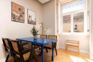 a blue table and chairs in a room with a window at Limehome Lisbon Rua do Arsenal in Lisbon +17 photos