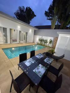 普吉市的住宿－Villa 3 bedrooms，游泳池旁的餐桌和椅子